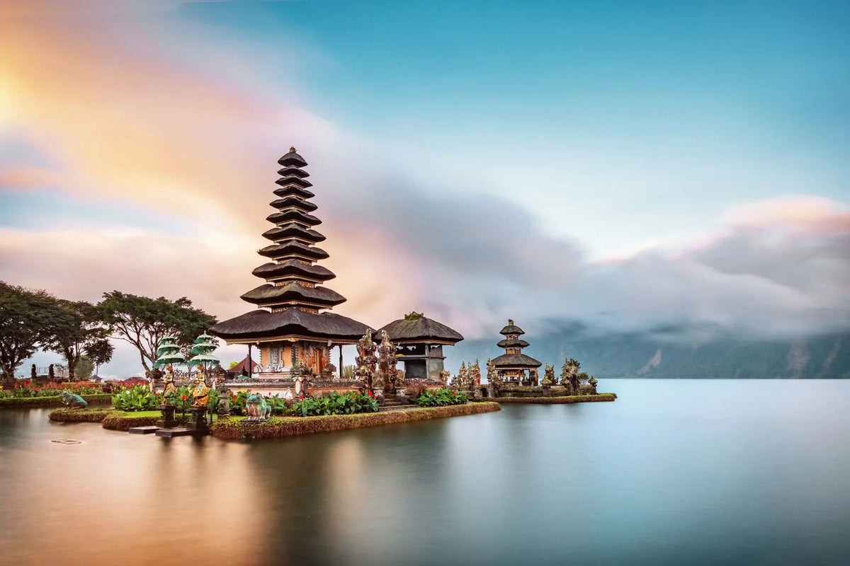Temple complex on an island with a rainbow in the background, located in a serene water setting.