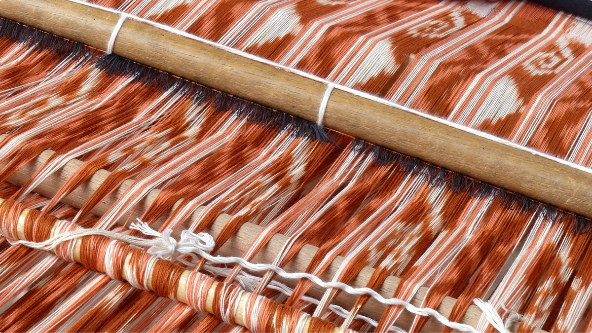 Warp ikat yarns being aligned on a traditional loom